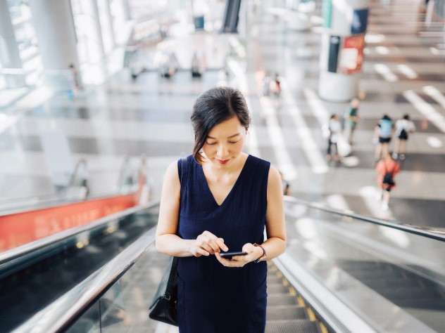 Frau mit Smartphone auf einer Rolltreppe